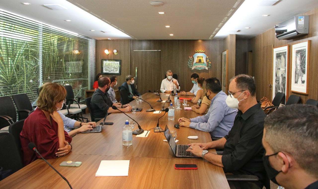 a foto mostra um grupo de pessoas sentadas em uma mesa de reunião